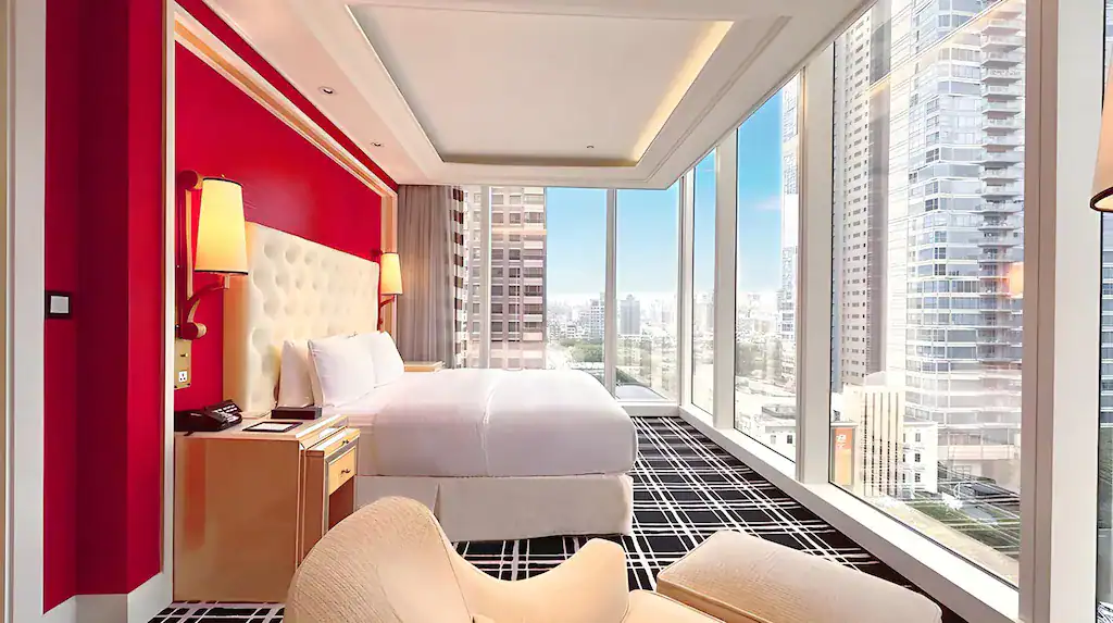 台中商旅客房大床與紅色主牆，落地窗外是城市高樓景觀