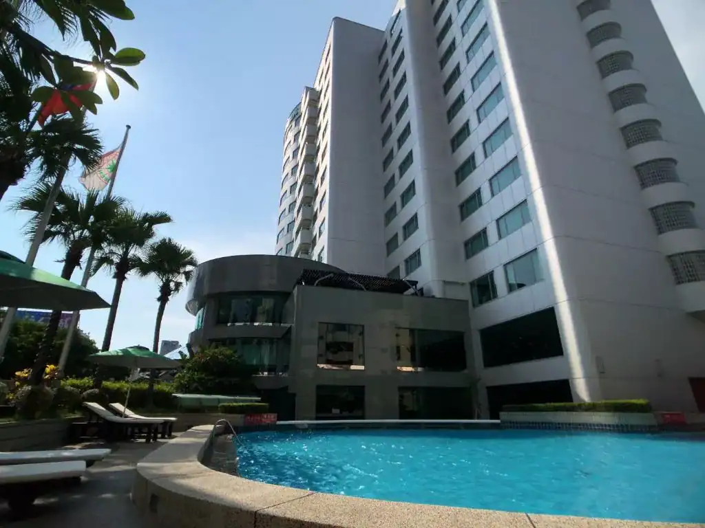 台中商旅外觀高樓建築與戶外泳池，池畔棕櫚樹圍繞出休憩區