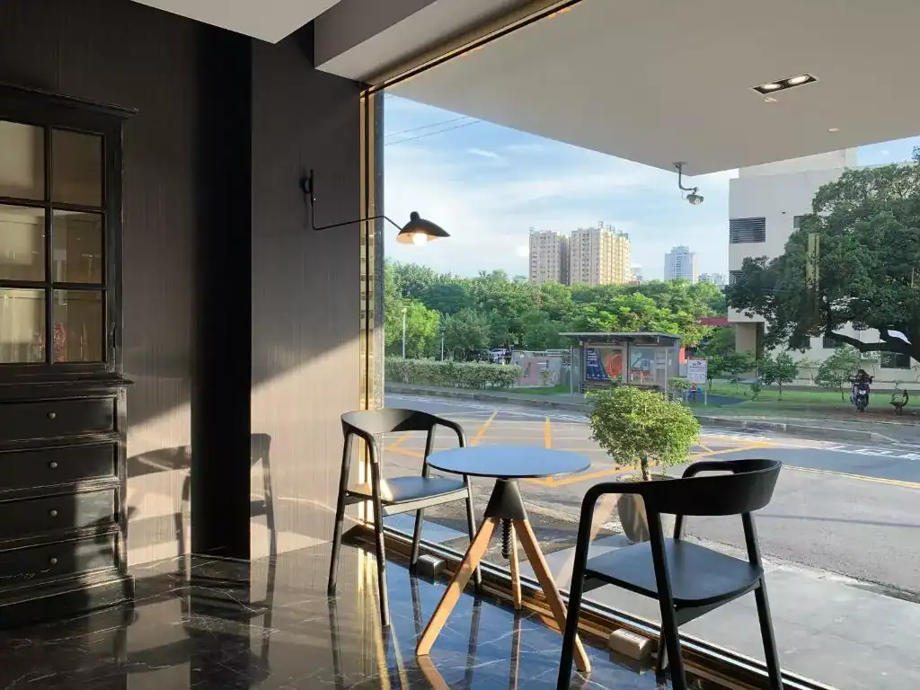 塔木德酒店台中台灣大道館戶外陽台空間畫面，設有簡約桌椅與大片開放式視野，可遠眺河岸綠意與城市景觀，環境清爽舒適且採光明亮，整體氛圍放鬆自在，是不少旅客規劃逢甲夜市附近住宿時會考慮的優質飯店選擇。
