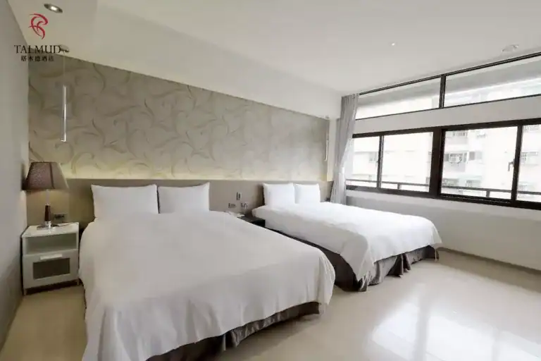 台中商旅推薦塔木德酒店台中台灣大道館雙床客房空間，包含兩張單人床與大面窗戶採光。