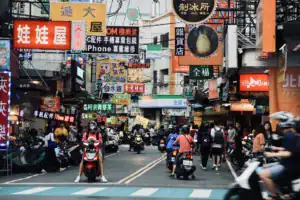 逢甲夜市街景畫面,街道兩側招牌密集且人潮眾多,機車與行人交錯呈現熱鬧市集氛圍,是選擇逢甲附近住宿旅客最期待的夜生活體驗之一。