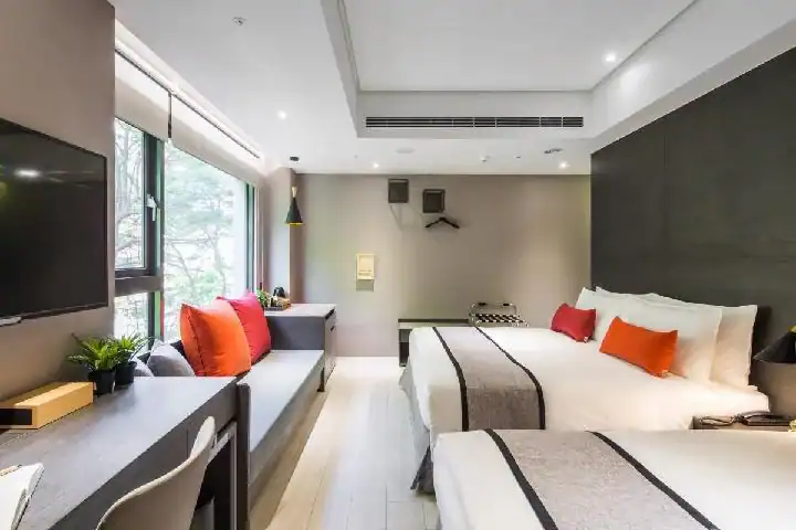 GOGO HOTEL 逢甲館客房空間,房內設有兩張床、沙發與書桌,大面窗景引入自然採光,是台中逢甲飯店常見的舒適住宿房型。