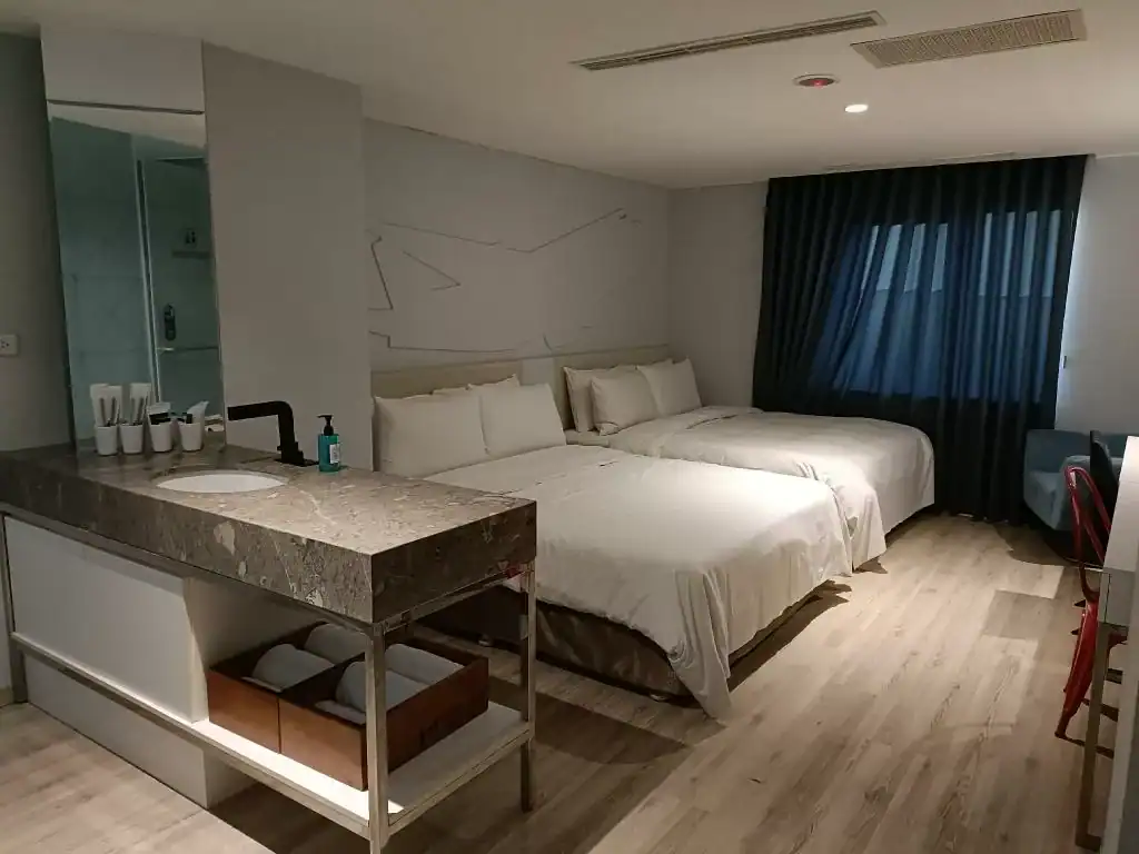 台中旅遊過夜推薦：飯店客房大床與深藍色窗簾，窗邊設有行李置放平台