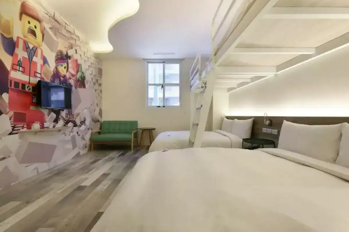 MINI HOTELS 逢甲館家庭房空間設計,房內設有上下舖床位、卡通主題壁畫與休憩沙發,為入住逢甲飯店的旅客提供活潑舒適的住宿環境。
