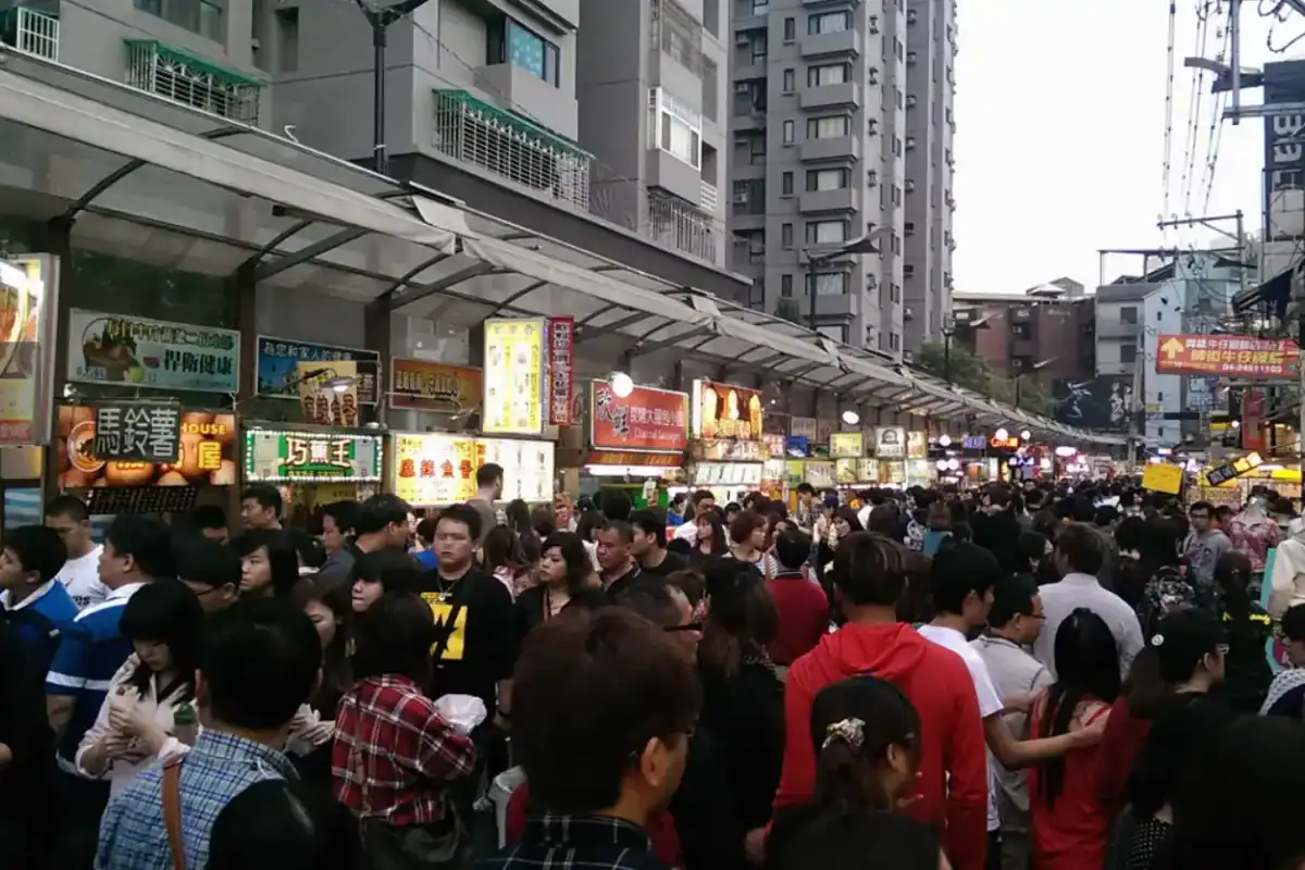 逢甲夜市傍晚時段人潮擁擠的街道景象,周邊聚集多間逢甲飯店與住宿旅館。