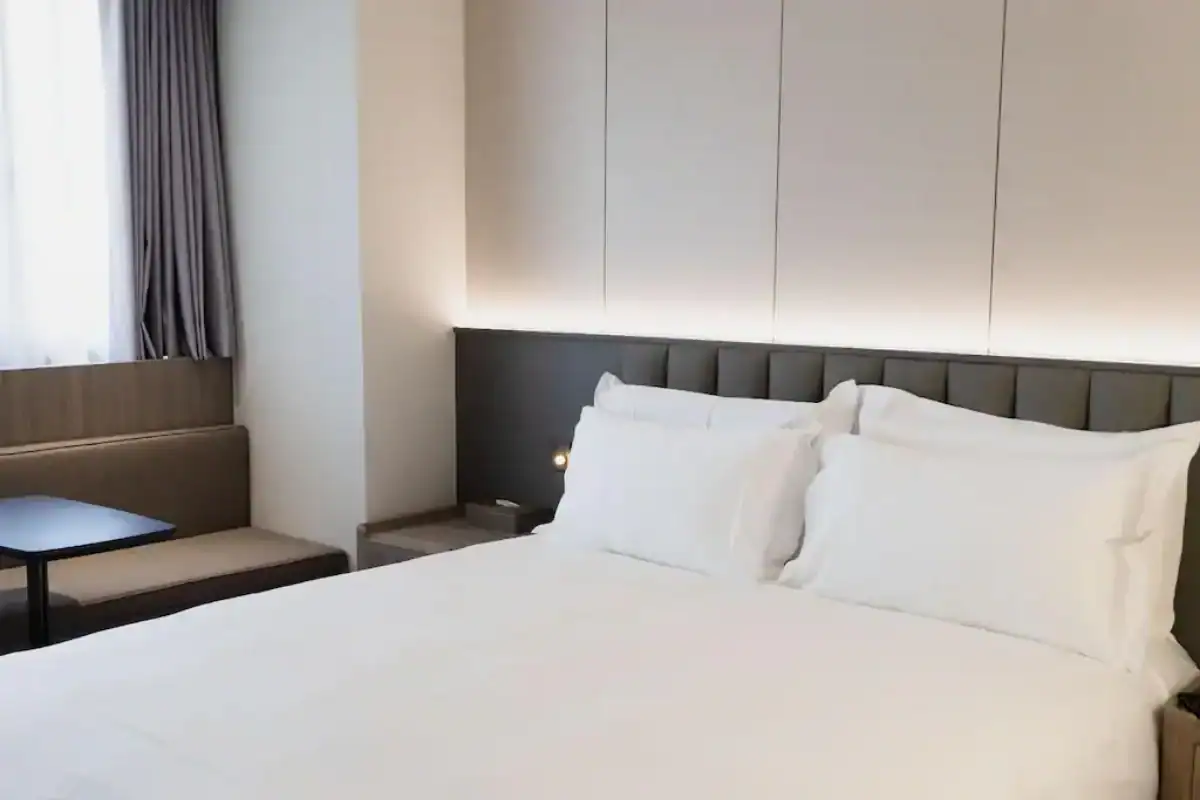 塔木德酒店台灣大道館大床房實景，白色寢具與窗邊座位配置，屬於台中便宜住宿選擇之一。