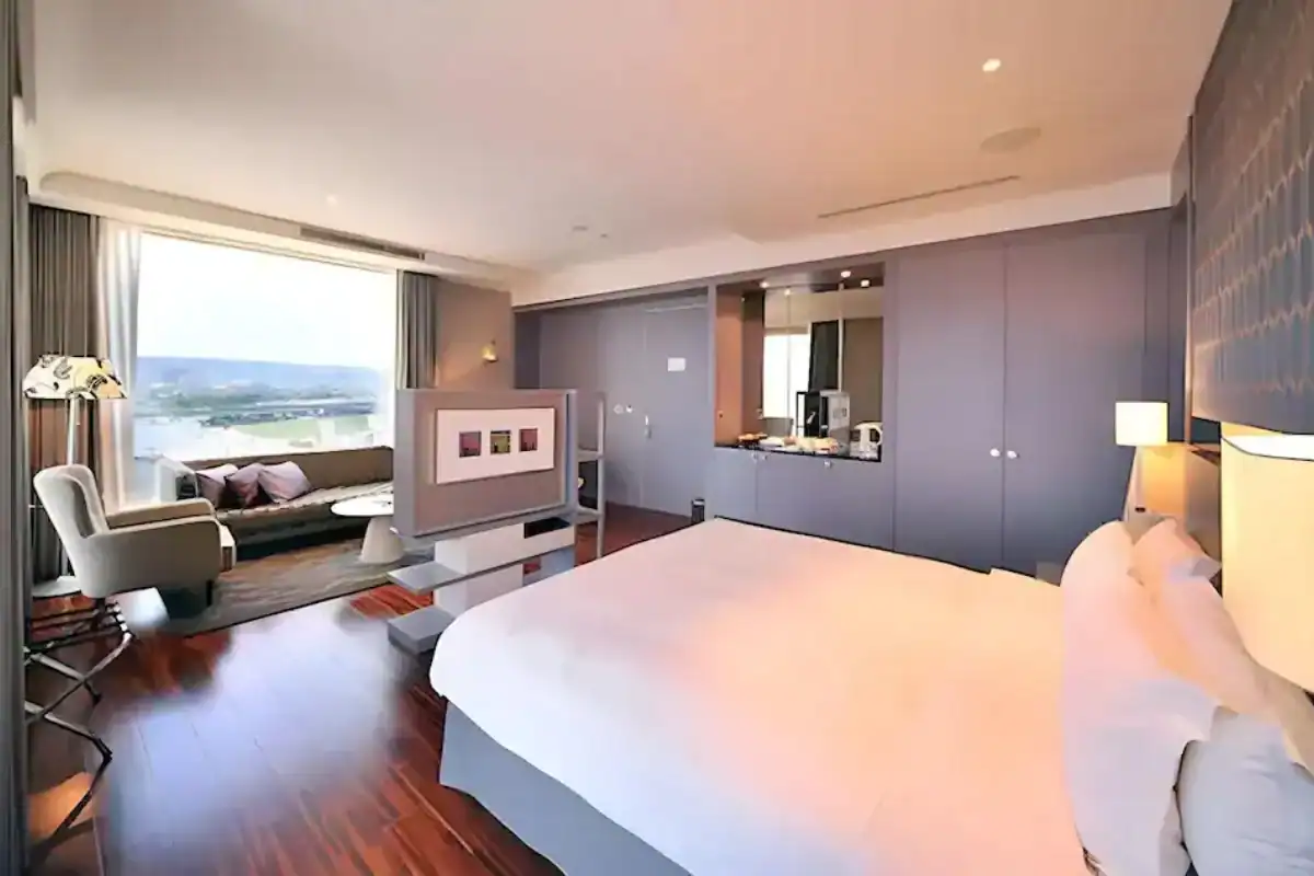 台中西屯區住宿 Hung’s Mansion 台中商旅，木地板客房配置大床，窗邊有沙發與單椅，房內採光明亮。