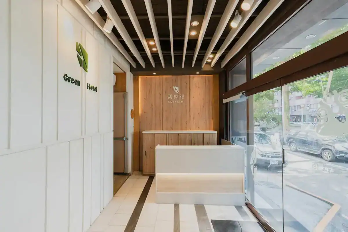 葉綠宿旅館逢甲館大廳接待空間設計,設有木質櫃檯與 Green Hotel 標誌,是台中逢甲飯店住宿選擇之一。
