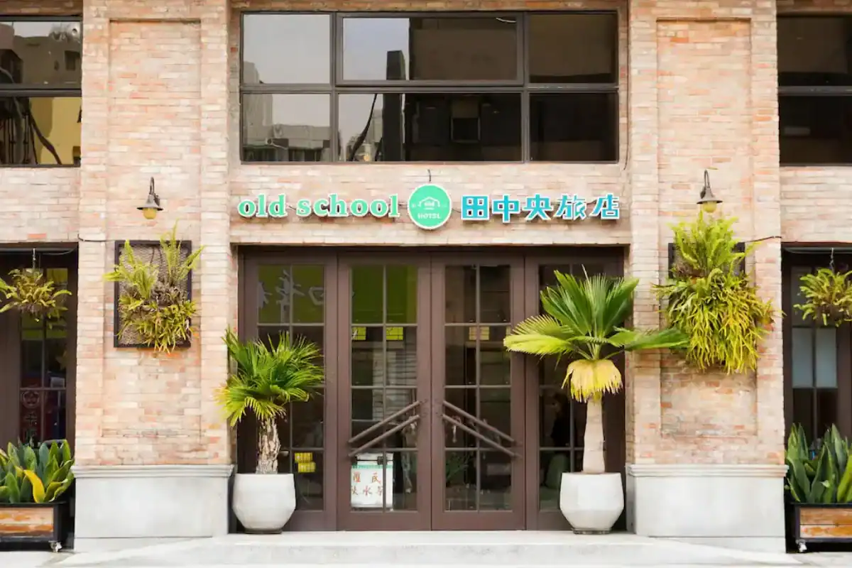 台中商旅：old school 行旅台中中央旅店的磚牆外觀與綠植入口，呈現溫暖復古風格的門面設計。