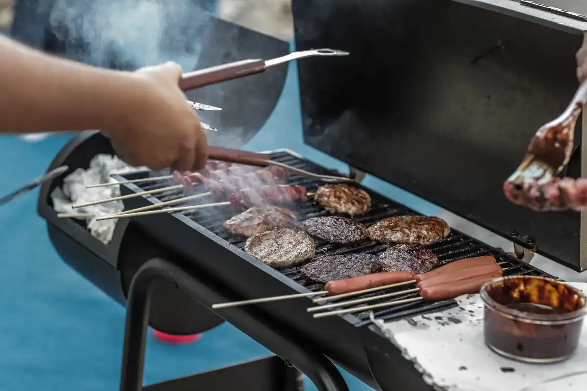 雙手在烤肉架上翻動肉排與串燒，決定台中烤肉地點要自備食材還是請園區代辦